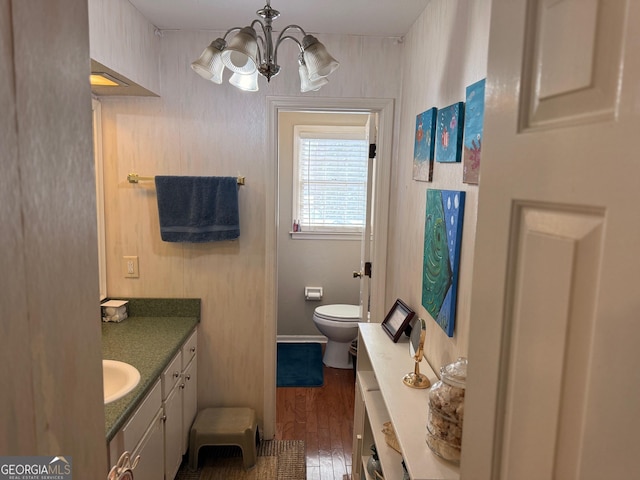 bathroom with vanity, hardwood / wood-style floors, an inviting chandelier, and toilet