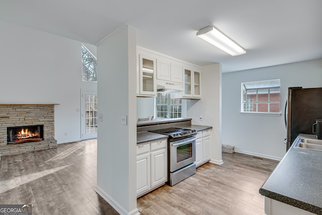 kitchen featuring sink, appliances with stainless steel finishes, a fireplace, light hardwood / wood-style floors, and white cabinets