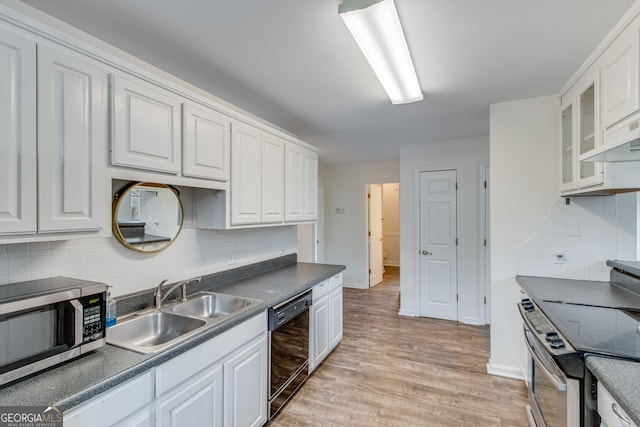 kitchen featuring sink, white cabinetry, light wood-type flooring, appliances with stainless steel finishes, and backsplash