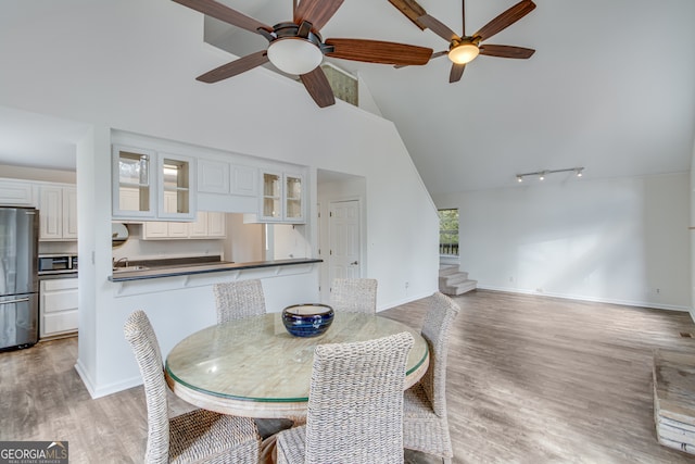 dining room with high vaulted ceiling, sink, ceiling fan, and light hardwood / wood-style flooring