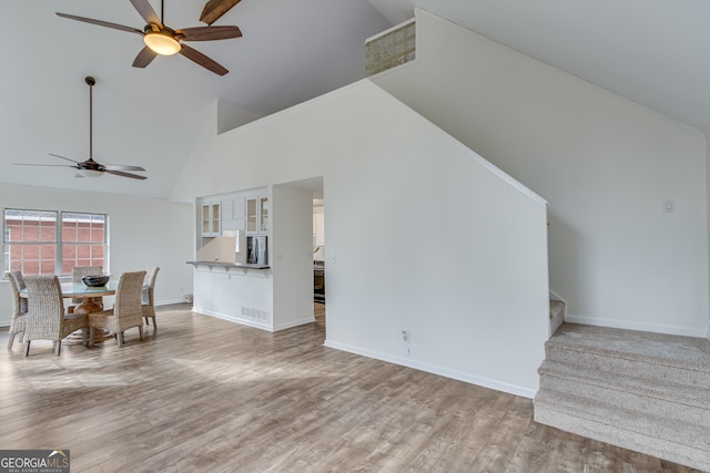 unfurnished living room with ceiling fan, light hardwood / wood-style floors, and high vaulted ceiling