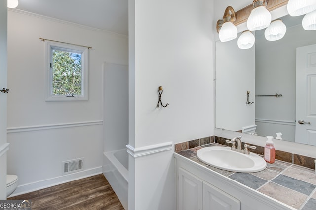 bathroom featuring vanity, hardwood / wood-style floors, crown molding, and toilet