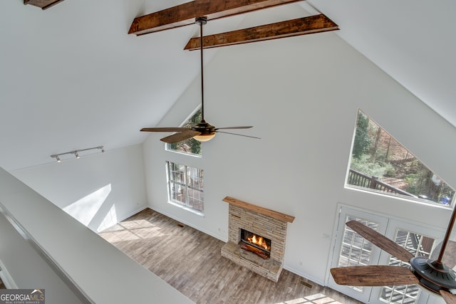 details with hardwood / wood-style flooring, ceiling fan, beam ceiling, a stone fireplace, and french doors