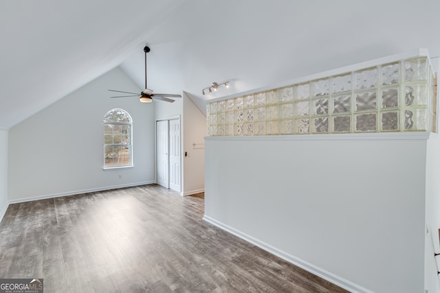 spare room featuring lofted ceiling, wood-type flooring, rail lighting, and ceiling fan