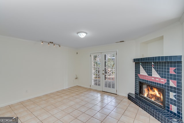 tiled living room featuring a tiled fireplace, crown molding, and french doors