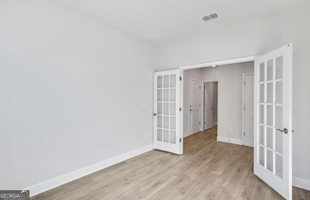 empty room featuring light wood-type flooring and french doors