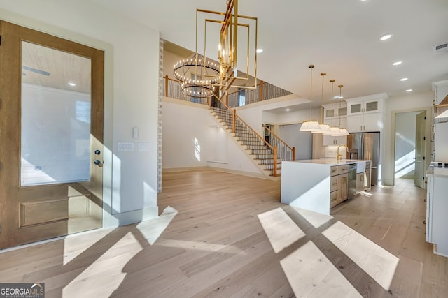 interior space featuring decorative light fixtures, a center island, light wood-type flooring, a notable chandelier, and white cabinets