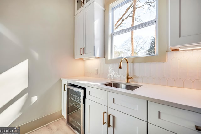 kitchen with white cabinetry, sink, wine cooler, decorative backsplash, and light hardwood / wood-style floors