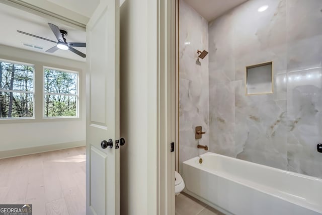 bathroom featuring tiled shower / bath combo, ceiling fan, and toilet