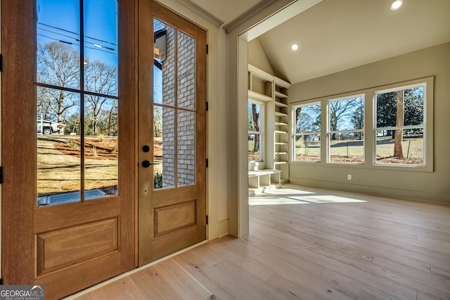 entryway with vaulted ceiling, built in features, and light hardwood / wood-style flooring