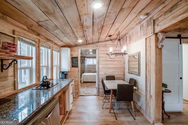 dining space featuring lofted ceiling, wood walls, light wood-type flooring, wooden ceiling, and a barn door