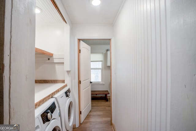 washroom featuring independent washer and dryer, ornamental molding, and light hardwood / wood-style flooring