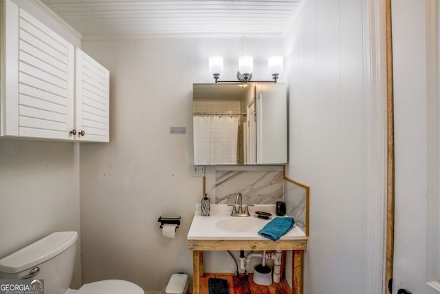 bathroom featuring ornamental molding, toilet, and sink