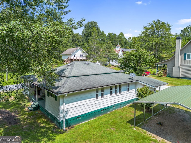 rear view of property with a carport and a yard