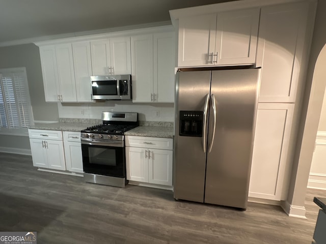 kitchen featuring light stone counters, appliances with stainless steel finishes, dark wood-type flooring, and white cabinets