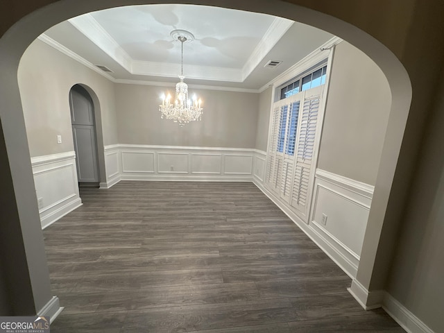 unfurnished dining area with an inviting chandelier, ornamental molding, dark hardwood / wood-style flooring, and a raised ceiling