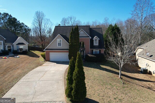 view of front property with cooling unit, a garage, and a front yard