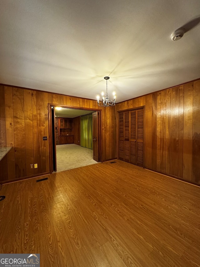 interior space featuring a notable chandelier, wooden walls, and light hardwood / wood-style floors