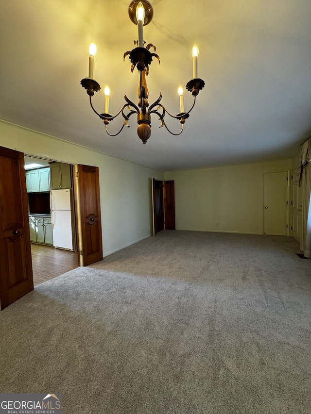 unfurnished room featuring a chandelier and carpet