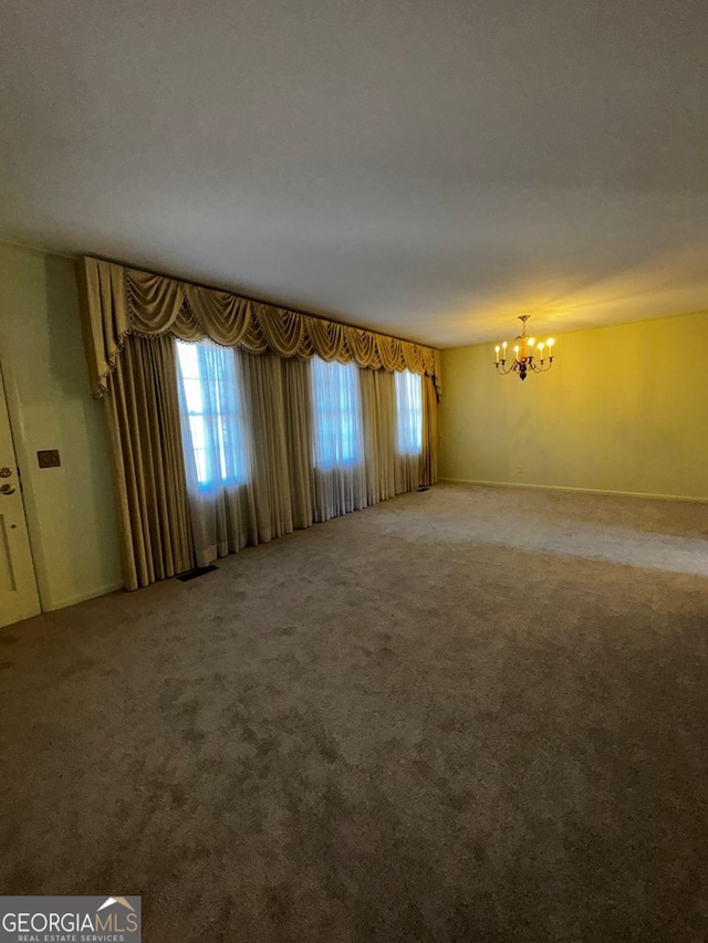 spare room featuring a notable chandelier and carpet