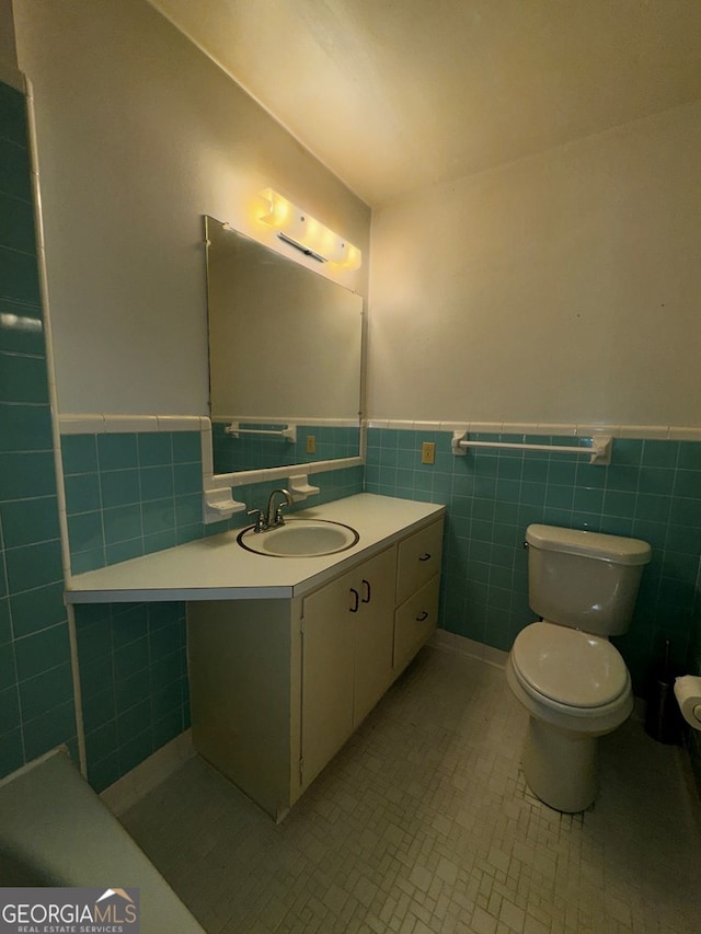 bathroom featuring tile patterned flooring, vanity, tile walls, and toilet