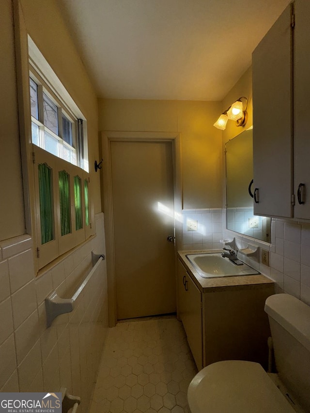 bathroom with tile walls, vanity, tasteful backsplash, tile patterned floors, and toilet