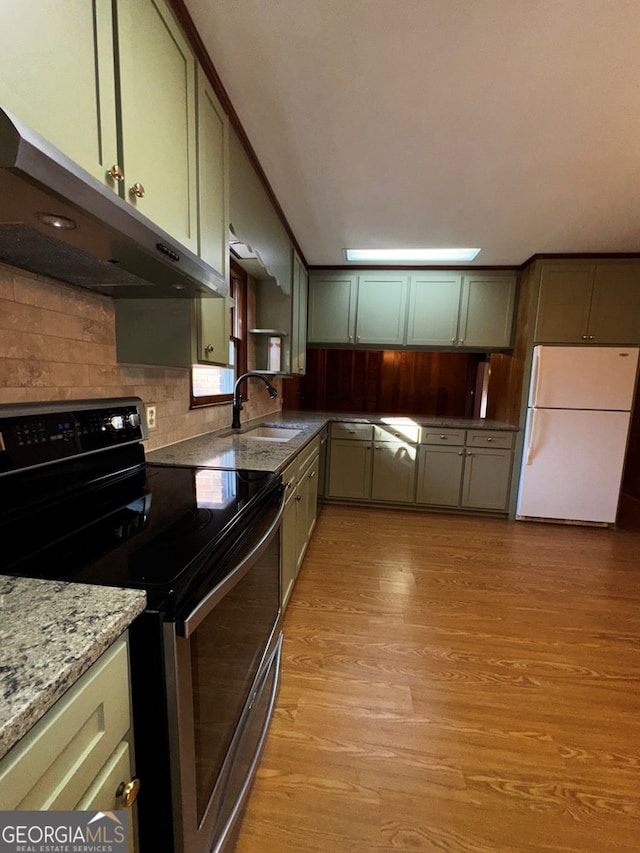 kitchen featuring stainless steel electric range oven, sink, white fridge, green cabinetry, and light hardwood / wood-style flooring