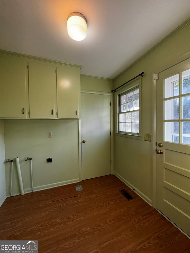 clothes washing area with cabinets and dark wood-type flooring