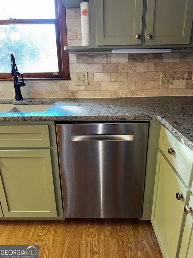 kitchen featuring green cabinetry, dishwasher, sink, and backsplash