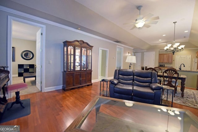 living room with ceiling fan with notable chandelier, ornamental molding, lofted ceiling, and hardwood / wood-style floors