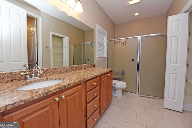 bathroom with a shower with door, vanity, tile patterned flooring, and toilet