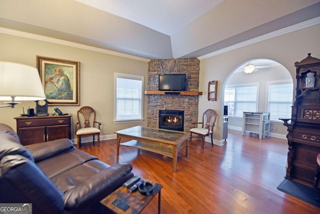 living room with lofted ceiling, a healthy amount of sunlight, a stone fireplace, and hardwood / wood-style floors