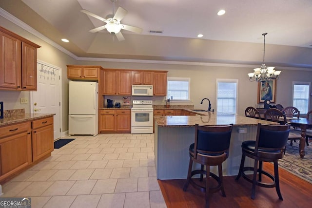 kitchen featuring sink, crown molding, a tray ceiling, a kitchen breakfast bar, and white appliances