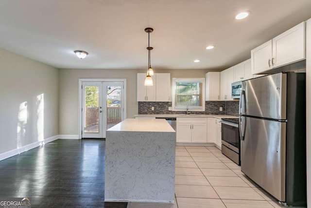 kitchen with appliances with stainless steel finishes, white cabinetry, hanging light fixtures, a center island, and french doors