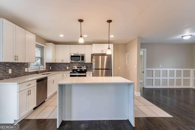 kitchen with sink, white cabinetry, a center island, appliances with stainless steel finishes, and pendant lighting