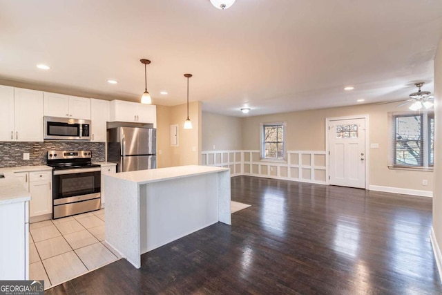 kitchen featuring appliances with stainless steel finishes, a kitchen island, hanging light fixtures, and white cabinets