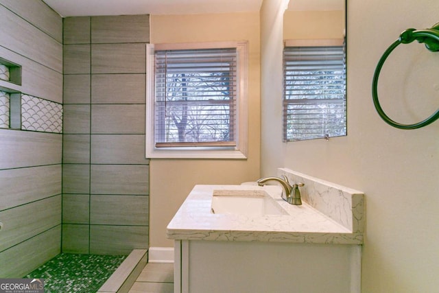 bathroom featuring tiled shower and vanity