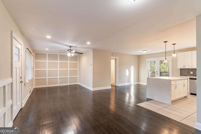 kitchen with light hardwood / wood-style flooring, white cabinetry, backsplash, decorative light fixtures, and stainless steel dishwasher