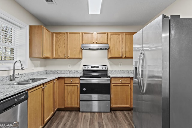 kitchen featuring dark hardwood / wood-style flooring, sink, light stone counters, and appliances with stainless steel finishes