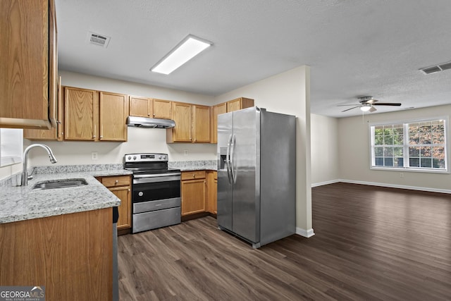 kitchen with dark hardwood / wood-style floors, sink, light stone counters, stainless steel appliances, and a textured ceiling