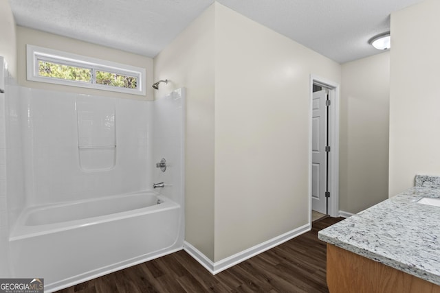 bathroom featuring wood-type flooring, shower / bathing tub combination, a textured ceiling, and vanity