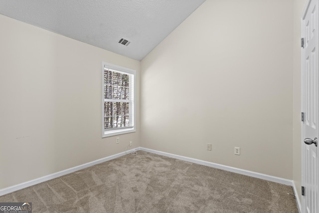 spare room with vaulted ceiling, light colored carpet, and a textured ceiling