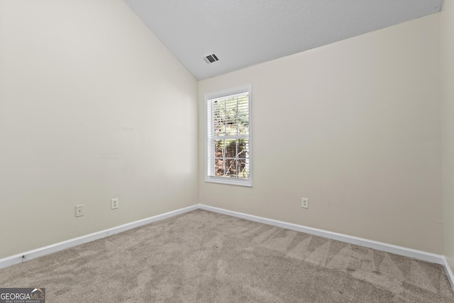 spare room with light colored carpet and lofted ceiling