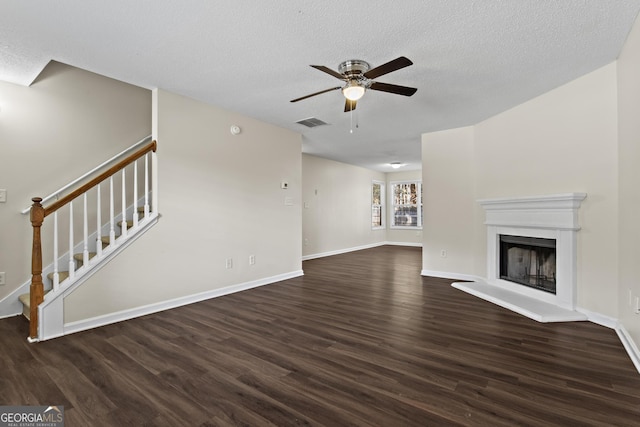 unfurnished living room featuring ceiling fan, dark hardwood / wood-style floors, and a textured ceiling