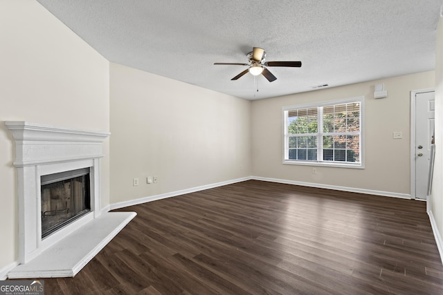 unfurnished living room with ceiling fan, dark hardwood / wood-style flooring, and a textured ceiling