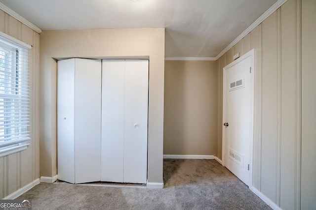 unfurnished bedroom featuring ornamental molding, light colored carpet, and a closet