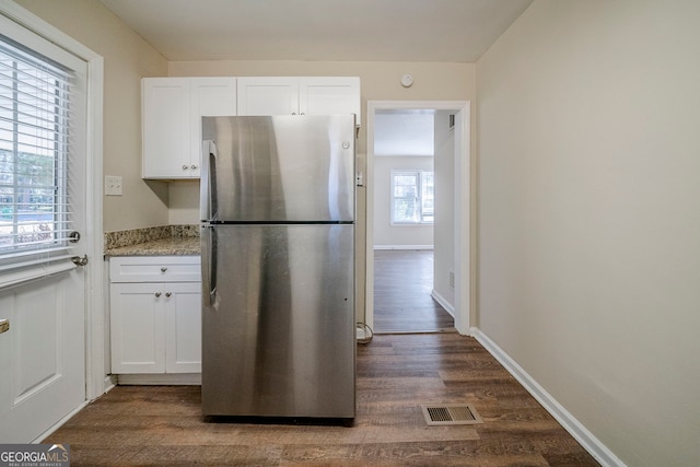 kitchen with white cabinetry, light stone countertops, dark hardwood / wood-style floors, and stainless steel fridge