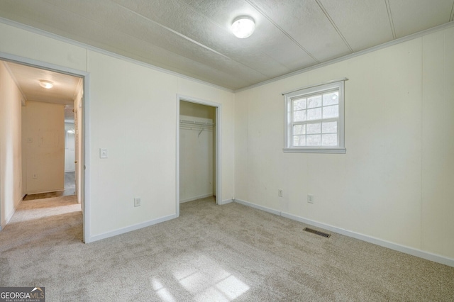 unfurnished bedroom featuring crown molding, light colored carpet, and a closet