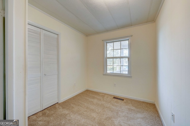 unfurnished bedroom with light carpet, ornamental molding, and a closet