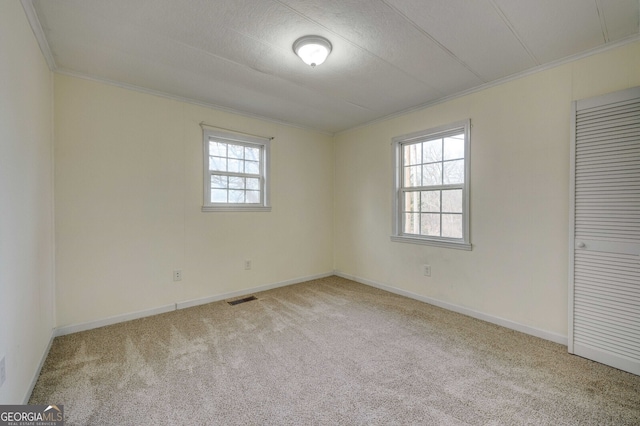 carpeted spare room featuring crown molding and plenty of natural light